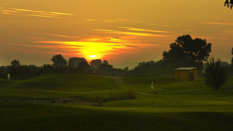 Diamond Country Club, © DCC Sunset over a golf course with flag and small building.