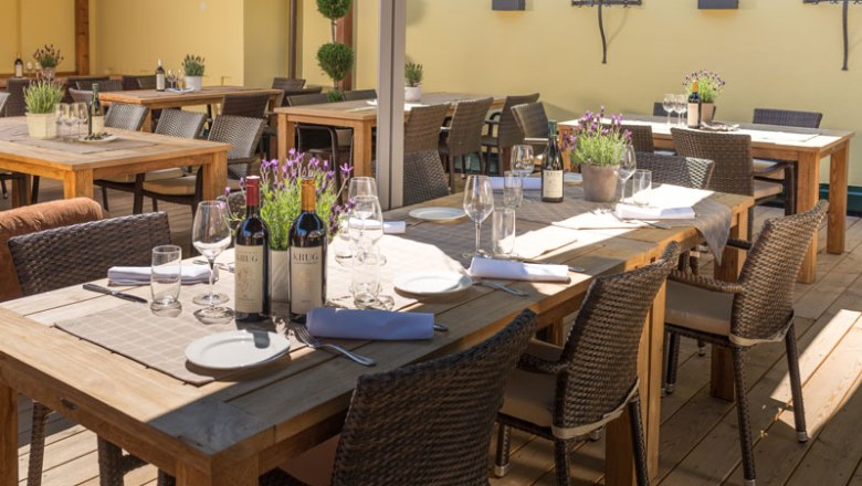 Terrace Altes Zechhaus, © Wastian A terrace with wooden tables set with bottles of wine, glasses and lavender in pots.