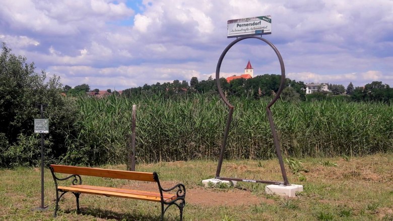 Beautiful view with rest area, © Marktgemeinde Pernersdorf A bench in front of a photo point with a view of a church in Pernersdorf.