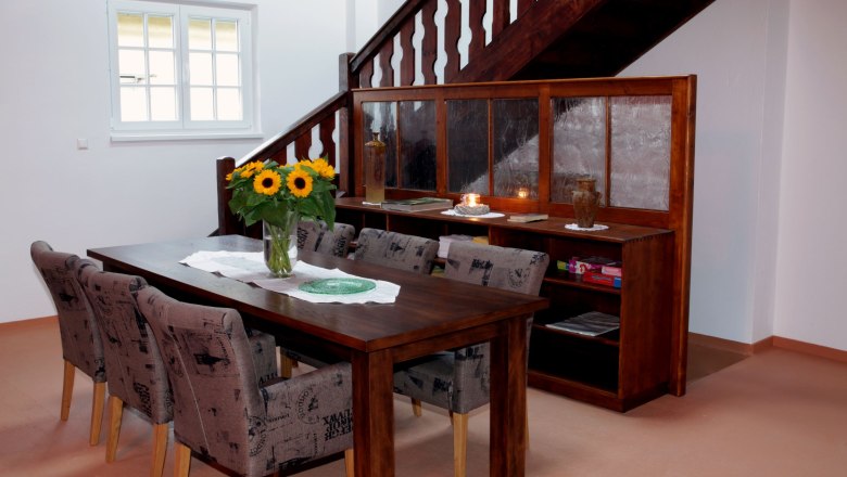 Dining table in Loft 1, © Carlos de Mello Dining area with wooden table, chairs and sunflowers in a loft.