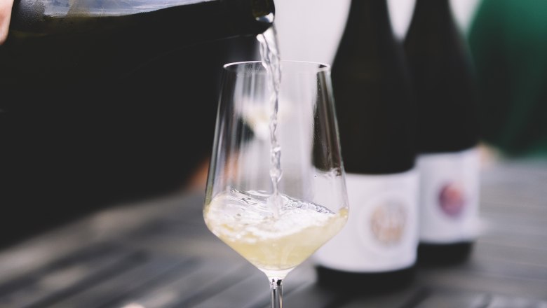 Pouring wine, © Niederösterreich Werbung / Mara Hohla White wine is poured into a glass on a table.