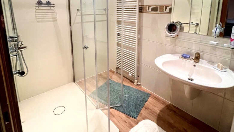 Bad_HeidisPlace, © Wiener Alpen Modern bathroom with shower, washbasin and heated towel rail.