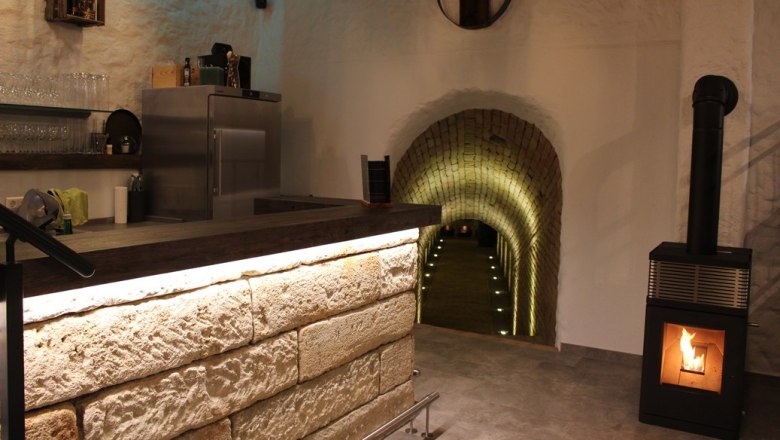 Wine shop, © Weingut Kerner Interior view of a wine bar with counter, fireplace and illuminated tunnel.