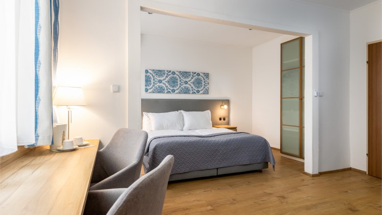 Hotel Zentral double room, © MartinHaider Fotografie/Hotel Zentral Schwartz GmbH Modern hotel room with double bed, desk and chair.