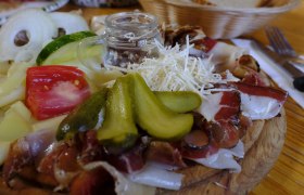 Symbol image, © www.pixabay.com A rustic platter with cheese, ham, gherkins, tomatoes and onions on a wooden table.