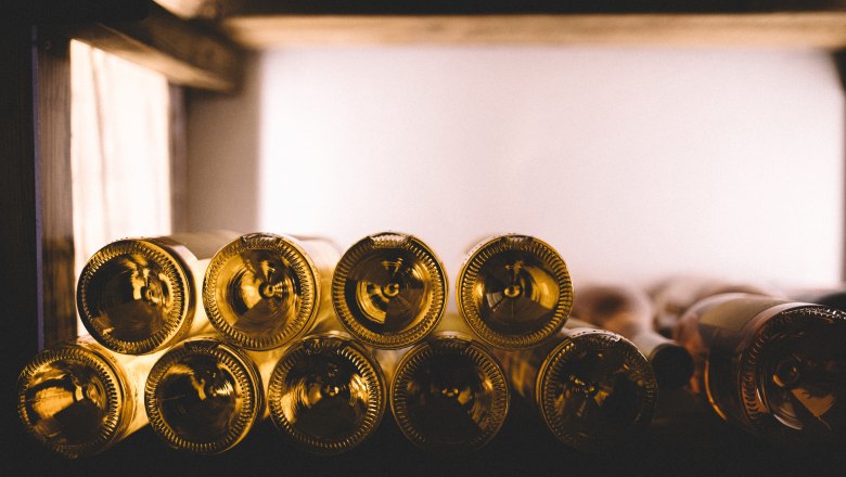 Well-stocked wine cellar, © Niederösterreich Werbung/Mara Hohla Close-up of wine bottles on a shelf, stacked horizontally.