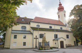 Heiligeneich parish church, © Richard Marschik Heiligeneich parish church with statue and cross in the foreground.