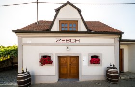 Wine cellar, © Fam. Zesch Small building with the inscription 'Zesch', two wine barrels and red flowers.