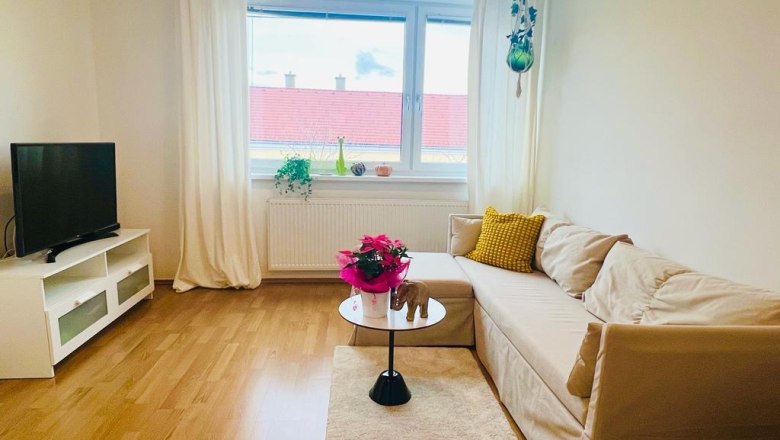 Living room apartment Café Frau Tinz, © Martina Lechner Bright living room with sofa, coffee table, TV and window with curtains.