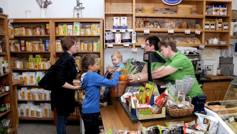 Gsunds Eck in Traismauer, © Evelyn Hochsteger A small store with customers and sales assistants standing at the counter. Shelves full of organic products in the background.