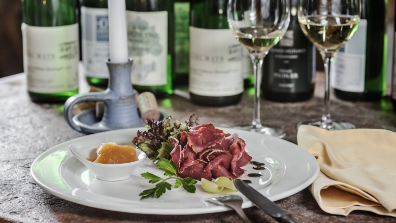 Sample meal from the Hotel Restaurant Zum Schwarzen Bären, © BOW Rita Newman A plate of ham, salad and chutney, surrounded by bottles of wine and glasses on a table.