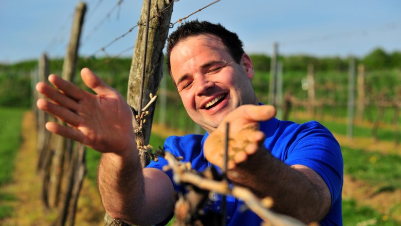 Winemaker Andreas Urban, © Seymann Man in blue shirt smiling in a vineyard.