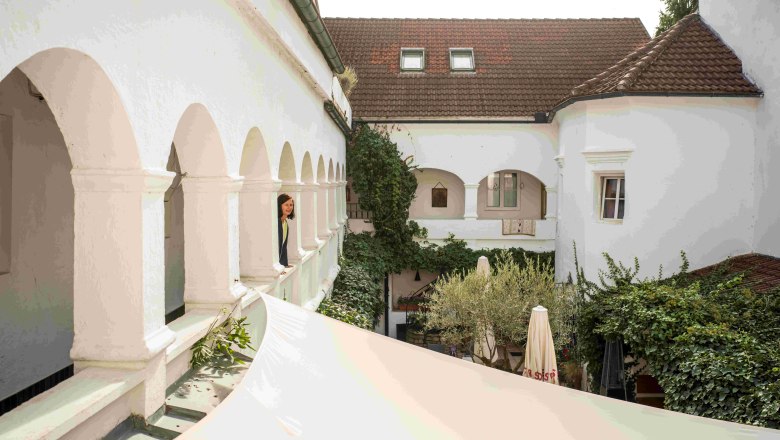 Maximahl arcade courtyard, © Robert Herbst Inner courtyard with arcades and plants, person looking out of an arched window.