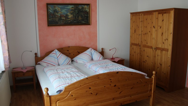 Multi-bed room, © Karl Buchner A bedroom with a double bed, two bedside tables, a closet and a painting on the wall.