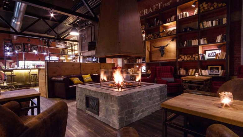 Living Room, © Derenko GmbH Cozy room with fireplace, wooden furniture and bookshelves.