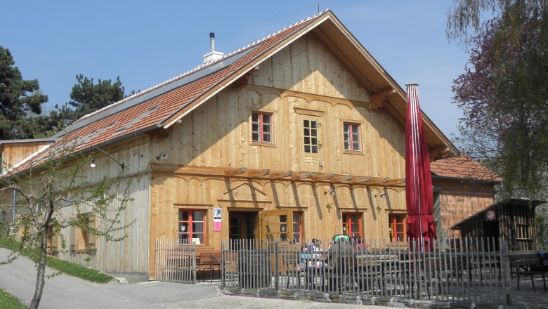Gasthaus Schwarzalm Krems, © Gasthaus Schwarzalm Krems Wooden building with red roof and fence, sunny day.