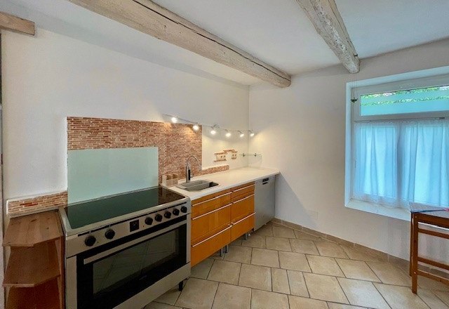 Kitchen, © Julia Grünschachner Modern kitchen with stove, wooden cupboards and tiled floor.
