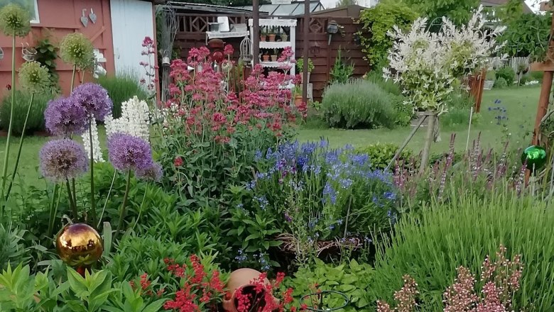 Perennial beds, © Susanne Bleier A lush perennial bed with colorful flowers and decorations in a garden.
