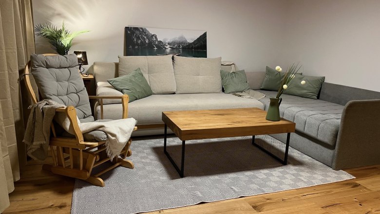 Living room sitting area, © Anita Gallei Cozy sitting area with grey sofa, wooden chair, wooden table and decoration in a living room.