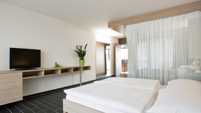 Sauvignon room, © Rosenberger Modern hotel room with double bed, TV and plants.