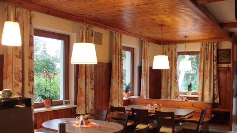 Restaurant, © Mühlendorfer Michael Cozy dining room with wooden furniture, large windows and hanging lamps.