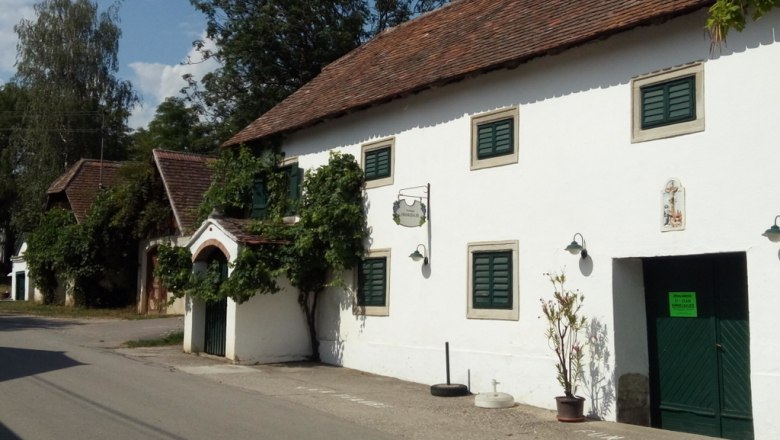 Weinut Himmelbauer, © Weinstraße Weinviertel White building with green shutters and an open door on a street.