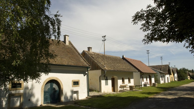 Digging, © Gemeinde Grabern Row of traditional wine cellars in Grabern, Austria, in sunny weather.