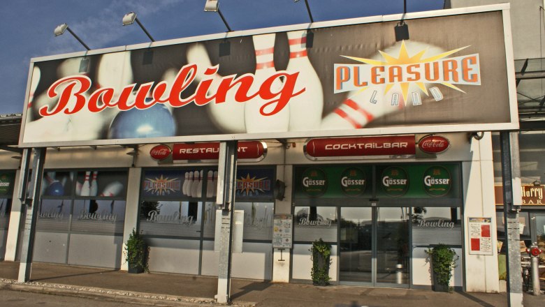 Pleasureland, © Wiener Alpen/Katrin Zeleny Entrance to a bowling center called Pleasureland with large signs and logos.