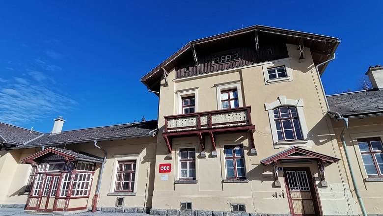 Railroad station Ausschlag-Zöbern, © Wiener Alpen, intern Historic station building with yellow façade and red wooden decor under a blue sky.