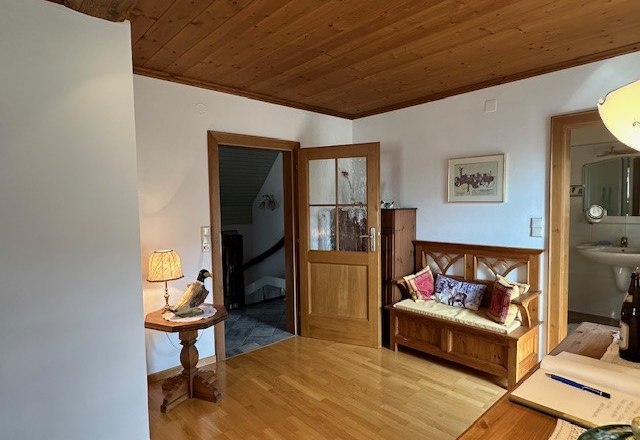 Bedroom with adjoining bathroom, © Heidi Peer Wood-paneled room with bench, table lamp and open access to a bathroom.