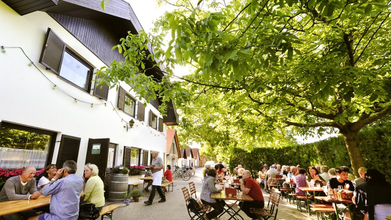 Wine tavern Nadler, © Nadler People sitting at outdoor tables under trees at a wine tavern.