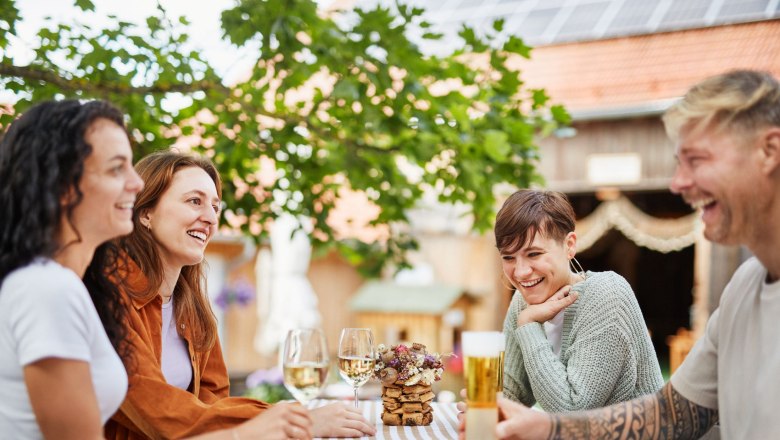 Mohnwirt Neuwiesinger, © © Waldviertel Tourismus, Gerhard Wasserbauer Four people sit laughing at an outdoor table with drinks.