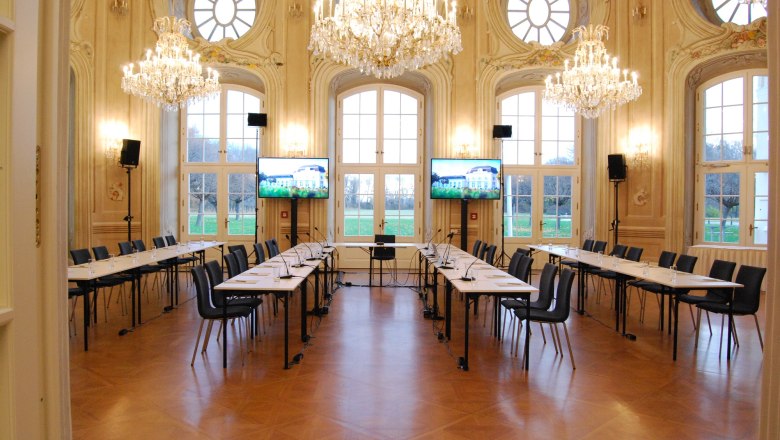 Conference Center Laxenburg, © Event Residenzen Niederösterreich Elegant conference room with chandeliers and large windows.