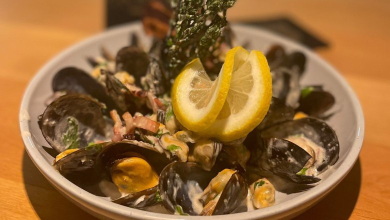 Mussels in the Freiherr, © Markus Jokesz A plate with mussels, cream sauce and lemon slices on a wooden table.