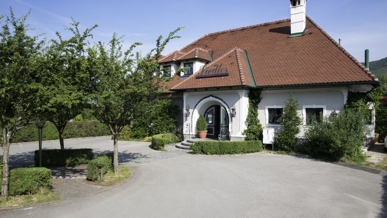 Wine tavern outside, © Monika Loeff Exterior view of a traditional wine tavern with a red tiled roof and green vegetation.