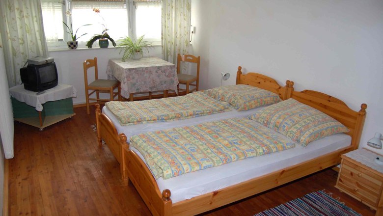 Rooms in the Weiss guest house, © Fam. Weiss A cozy guest room with a double bed, small table, two chairs and an old TV.