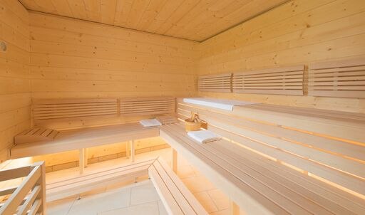 Sauna in the wellness pavilion, © Elisabeth Samek Interior view of a modern sauna with wooden benches and towels.