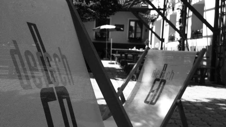 Deckchairs, © Dersch Black and white photo of deckchairs outside in front of a building.