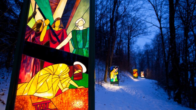 St. Ulrich's Church and the Glass Way of the Cross, © Thermengemeinden The illuminated stations of the Stations of the Cross made of colored glass on a winter evening with snow