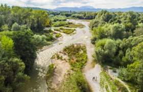 Natural spectacle Leitha spring, © Wiener Alpen/ fueloep Aerial view of the branched Leitha and gravel bed in a green landscape with trees and mountains in the background.