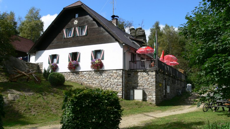 Fogstone hut, © Waldviertel Tourismus A mountain hut with flowers and parasols on a terrace.