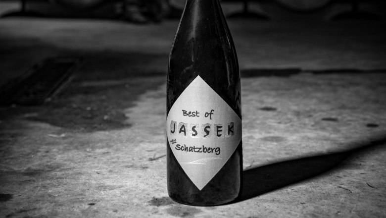 Jassek_Keller(c)MartinLifkaPhotography_OK_780x440, © Martin Lifka Photography Black and white photo of a wine bottle with the label 'Best of Jassek Schatzberg' on a concrete floor.
