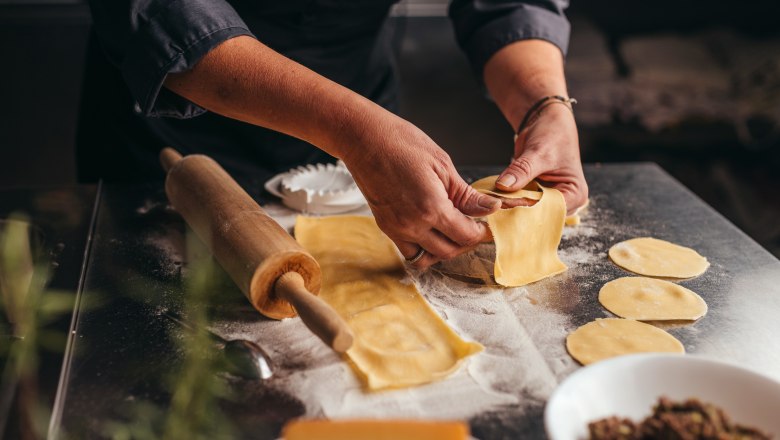 Homemade pasta, © Niederösterreich Werbung/Daniela Führer Person forms dumplings on a floured work surface.