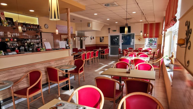Cafe Lechner interior, © Bäckerei Lechner Interior view of a café with red chairs and tables, bar area on the left.