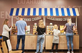 Taste herbs and spices, © © Waldviertel Tourismus, Gerhard Wasserbauer People sample products at a stand with a blue and white roof.