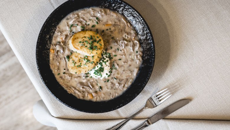 Beuschl with bread dumplings, © Niederösterreich Werbung/David Schreiber A plate with Beuschl and two bread dumplings, garnished with chives, on a table with cutlery.