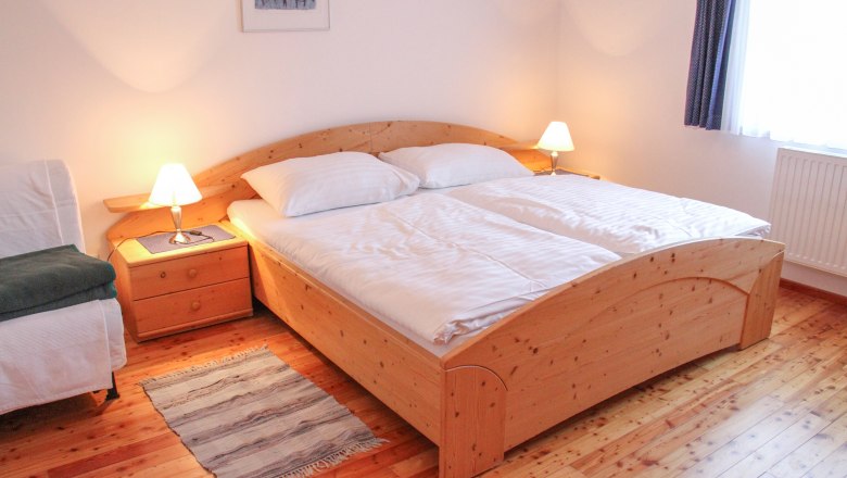 Apartment 70m², © Haus Lenz Cozy bedroom with double bed, wooden floor and bedside tables with lamps.
