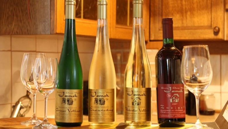 Wine from our own production, © Jamek Four wine bottles and glasses on a table in a kitchen.