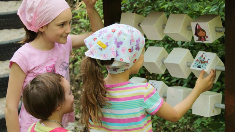 Fairytale forest, © Tanja Schwartz Three children playing on a piece of wooden outdoor play equipment.
