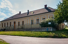 Museum of local history, © Marktgemeinde Jedenspeigen A yellow building with several windows and a fence in front of it, surrounded by trees and a lawn.